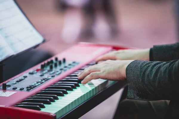 Concert view of a musical keyboard piano player during musical jazz band orchestra performing, keyboardist hands during concert, male pianist on stage, hands close-up