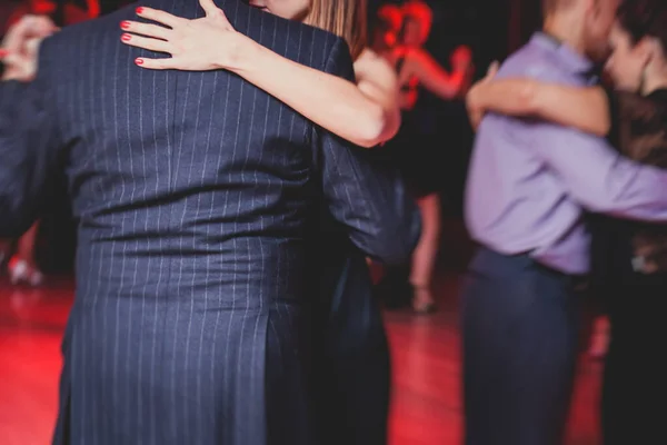 Couples dancing argentinian dance milonga in the ballroom, tango lesson in the red lights, dance festival