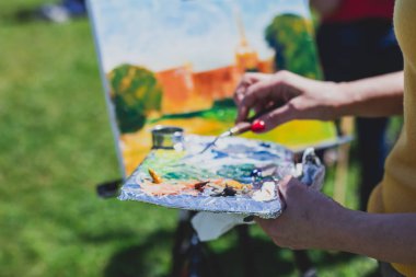 Plein boyama süreci, parktaki resim sehpaları ve açık havada suluboya resim dersi sırasında tuvalleri olan bir grup yetenekli öğrenci. 