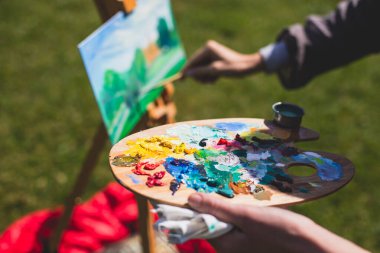 Plein boyama süreci, parktaki resim sehpaları ve açık havada suluboya resim dersi sırasında tuvalleri olan bir grup yetenekli öğrenci. 