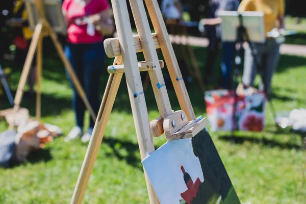 Process of plein air painting, group class of adult talented students in the park with paints easels, and canvases during lesson of watercolour painting outdoors