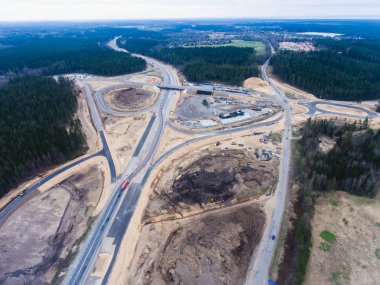 Ağır bir araç, buldozer ve kazıcı ile büyük bir inşaat alanının hava görüntüsü, yeni bir yol yapımı, inşaat sırasında çalışan ve boşaltan kum ve karayolu metali, insansız hava aracından çekilen