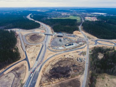 Ağır bir araç, buldozer ve kazıcı ile büyük bir inşaat alanının hava görüntüsü, yeni bir yol yapımı, inşaat sırasında çalışan ve boşaltan kum ve karayolu metali, insansız hava aracından çekilen