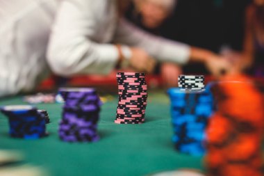 Çok renkli kumarhane masasının canlı bir görüntüsü. Rulet oynanıyor, kumarhane fişleri takılıyor. Krupiye, para ve bir grup zengin kumarbazın eli...