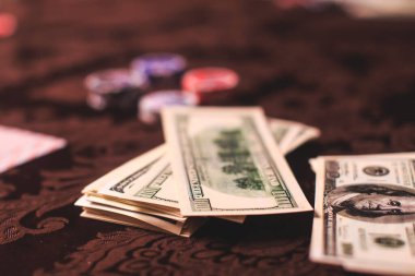 Poker masası, bir deste kart, jeton, alkol, dolar parası ve poker oynayan zengin insanlar.