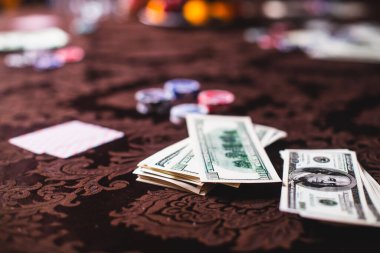 Poker masası, bir deste kart, jeton, alkol, dolar parası ve poker oynayan zengin insanlar.