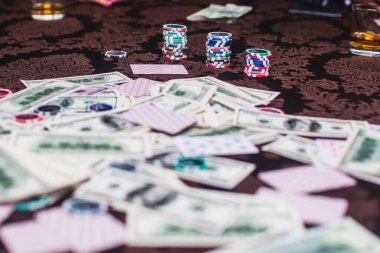 Poker masası, bir deste kart, jeton, alkol, dolar parası ve poker oynayan zengin insanlar.