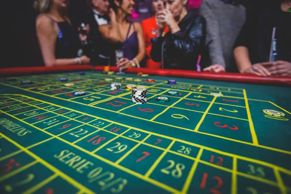 カジノチップを使用して 動きのあるルーレット付きのマルチカラーカジノテーブルのクローズアップ活気のあるイメージ クワイパーとモンとギャンブルの富裕層の手によって — ストック写真