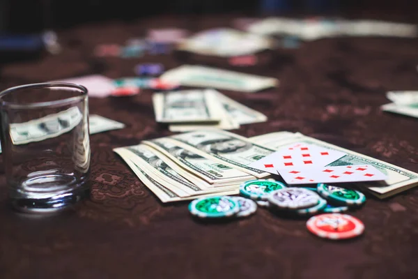 Poker masası, bir deste kart, jeton, alkol, dolar parası ve poker oynayan zengin insanlar.