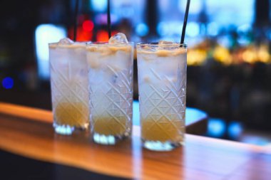 Bir partide, martinide, votkada ve diğerlerinde, açık hava etkinliğinde, arka planda barmen olan dekore edilmiş yemek masasında güzel renkli alkollü kokteyller.