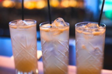 Bir partide, martinide, votkada ve diğerlerinde, açık hava etkinliğinde, arka planda barmen olan dekore edilmiş yemek masasında güzel renkli alkollü kokteyller.