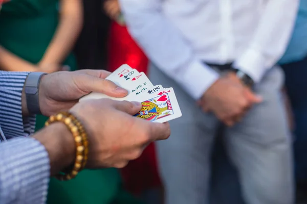 Magician showing card tricks focus in front of guests on party event wedding celebration, juggler performing show, summer day