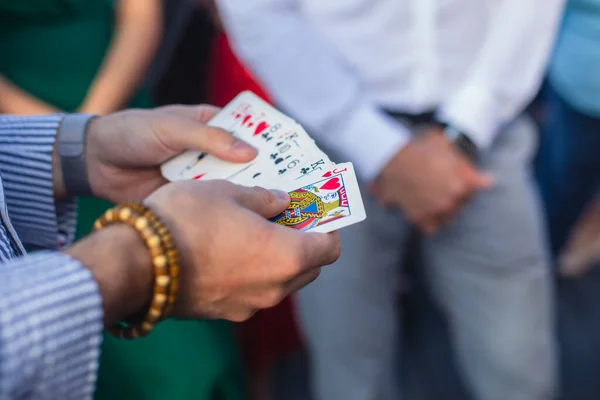 Magician showing card tricks focus in front of guests on party event wedding celebration, juggler performing show, summer day