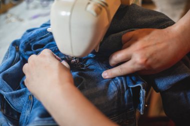 Evde kot pantolon tamir etme ve dikme süreci, dikiş makinesine kot pantolon iliştirme, kadın terzinin eliyle terzilik, terzilik, terzilik ve kot pantolon dikme ve dikiş.