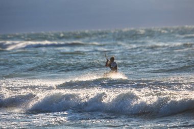 Profesyonel uçurtma sörfçüsü sörfçü sörfçü açık denizde dalgalarda yüzer, su sıçratır, uçurtma uçurur, uçurtma sörfü yapar yaz günü aşırı eğlenceli su sporları yapar.