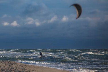 Profesyonel uçurtma sörfçüsü sörfçü sörfçü açık denizde dalgalarda yüzer, su sıçratır, uçurtma uçurur, uçurtma sörfü yapar yaz günü aşırı eğlenceli su sporları yapar.