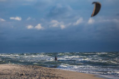 Profesyonel uçurtma sörfçüsü sörfçü sörfçü açık denizde dalgalarda yüzer, su sıçratır, uçurtma uçurur, uçurtma sörfü yapar yaz günü aşırı eğlenceli su sporları yapar.
