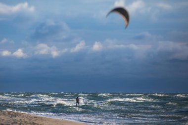 Profesyonel uçurtma sörfçüsü sörfçü sörfçü açık denizde dalgalarda yüzer, su sıçratır, uçurtma uçurur, uçurtma sörfü yapar yaz günü aşırı eğlenceli su sporları yapar.