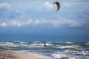 Profesyonel uçurtma sörfçüsü sörfçü sörfçü açık denizde dalgalarda yüzer, su sıçratır, uçurtma uçurur, uçurtma sörfü yapar yaz günü aşırı eğlenceli su sporları yapar.