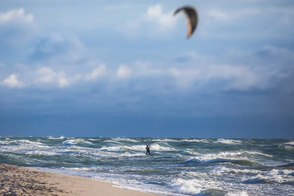 Profesyonel uçurtma sörfçüsü sörfçü sörfçü açık denizde dalgalarda yüzer, su sıçratır, uçurtma uçurur, uçurtma sörfü yapar yaz günü aşırı eğlenceli su sporları yapar.