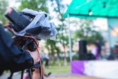 TV haberlerinde çalışan bir kameraman, konserin çevrimiçi yayınlanması, kameralı profesyonel videograf, canlı yayın, yağmurlu da