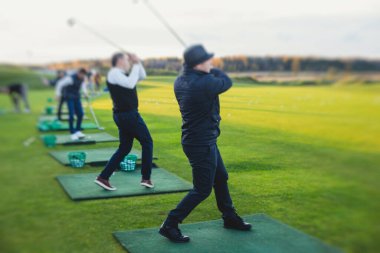 Golf antrenmanında antrenman yapan ve antrenman yapan bir grup golfçü, golf sahasında oynayan erkekler, golf klübünde golf oynayan erkekler, yaz güneşli da.