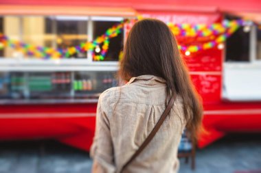 Renkli yemek kamyonunda yemek siparişi veren bir kız. Yemek festivali, yaz tatili.