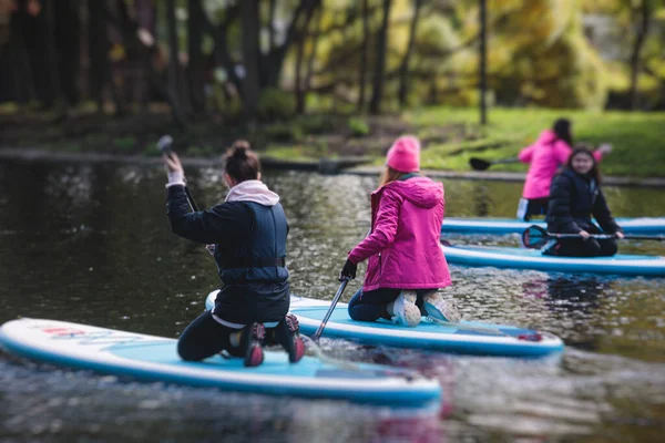 Group of sup surfers stand up paddle board, women stand up paddling together in the city river and canal in summer sunny da