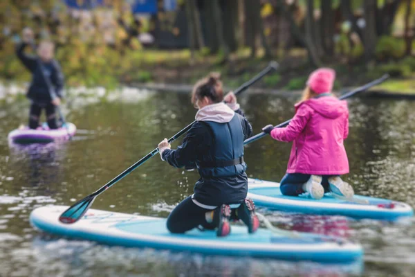 Group of sup surfers stand up paddle board, women stand up paddling together in the city river and canal in summer sunny da