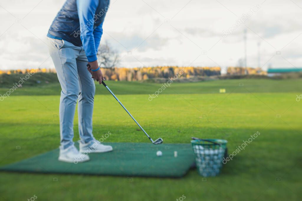 Group of golfers practicing and training golf swing on driving range practice, men playing on golf course, golf ball at golfing complex club resort, summer sunny da