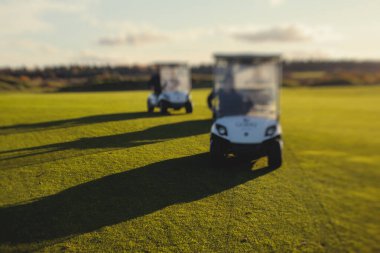 Golf elektrikli arabaları gün içinde golf sahasında, golf arabaları tatil köyünde golfçülerle sürüyor.