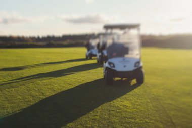 Golf elektrikli arabaları gün içinde golf sahasında, golf arabaları tatil köyünde golfçülerle sürüyor.
