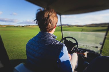 Golf elektrikli arabaları gün içinde golf sahasında, golf arabaları tatil köyünde golfçülerle sürüyor.