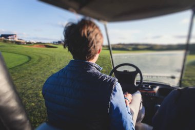 Golf elektrikli arabaları gün içinde golf sahasında, golf arabaları tatil köyünde golfçülerle sürüyor.