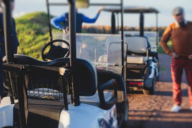 Golf elektrikli arabaları gün içinde golf sahasında, golf arabaları tatil köyünde golfçülerle sürüyor.