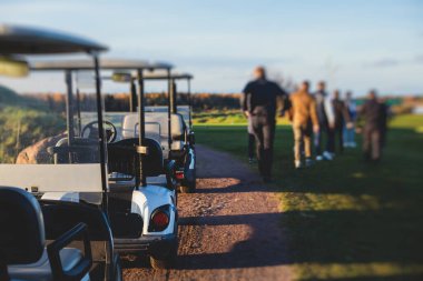 Golf elektrikli arabaları gün içinde golf sahasında, golf arabaları tatil köyünde golfçülerle sürüyor.