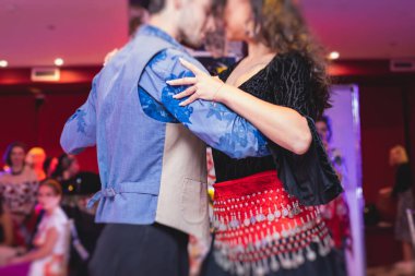 Kırmızı etek giyen ve balo salonunda geleneksel çingene dansı yapan çift ve kadınlar.