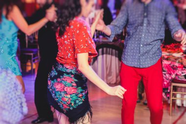 Kırmızı etek giyen ve balo salonunda geleneksel çingene dansı yapan çift ve kadınlar.