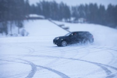 Kar ve buzda sürüklenen SUV arabası, yarışma sırasında, kışın karlı yarış pistinde sürükleniyor.