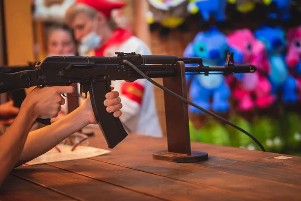 People aiming and shooting in target at a shooting firing range gallery in carnival amusement park