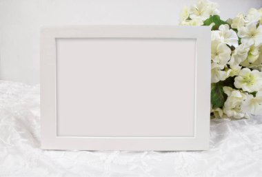 Güzel bir 5x7 beyaz çerçeve beyaz ortancalarla süslenmiş beyaz dantelli bir arka plana lüks bir şekilde dayanır..