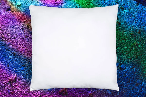 Square white throw pillow resting on a colorful textured background.