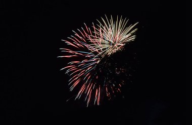 Karanlık yaz gökyüzünde patlayan pembe ve mavi havai fişekler..