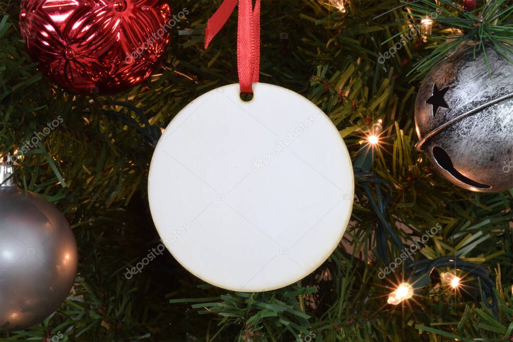 Blank Round Christmas Ornament hanging from a lit up Christmas tree surrounded by ornaments. 