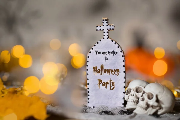 You are invited to Halloween party. Grave and two skulls. Halloween background