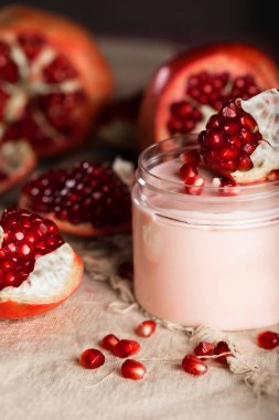 Pomegranate body cream on a wooden surface. Closeup clipart