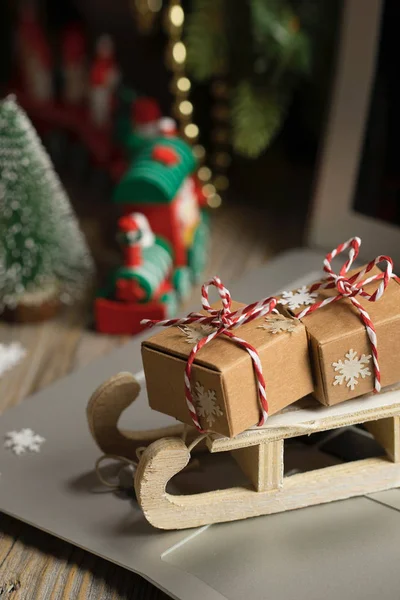 Kleiner Holzschlitten Mit Weihnachtsgeschenken Auf Einem Laptop Nahaufnahme — Stockfoto