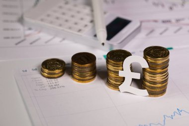 Kesme sikke yığını, İngiliz Sterlini. Arka planda bir kalem ile hesap makinesi