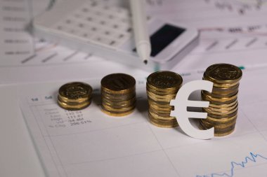 Euro simgesi sikke yığını, kesme. Arka planda bir kalem ile hesap makinesi
