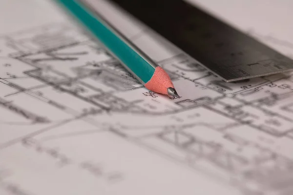 Coal pencil and metal ruler on a technical drawing of an apartment. Closeup